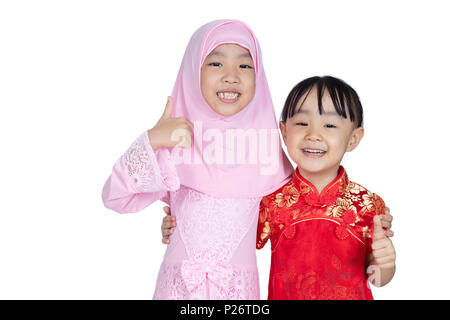 Asian Chinese little sisters wearing cheongsam and traditional Malay costume with thumbs up in isolated white background Stock Photo