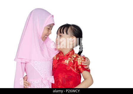 Asian Chinese little sisters wearing cheongsam and traditional Malay costume in isolated white background Stock Photo