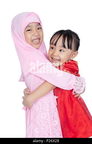 Asian Chinese little sisters wearing cheongsam and traditional Malay costume in isolated white background Stock Photo