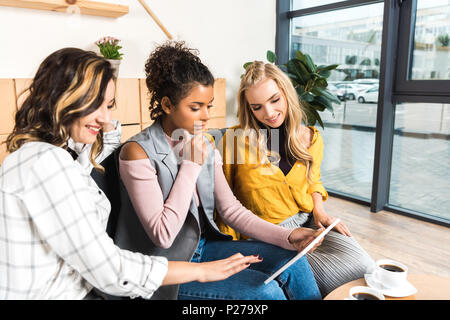 group of beautiful girlfriends using tablet together in cafe Stock Photo