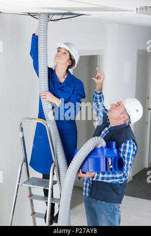 two electricians working on the ceiling Stock Photo