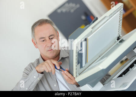 mature male technician repairing digital photocopier machine Stock Photo
