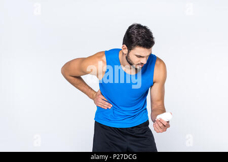 young man with stomachache looking at jar of pills isolated on white Stock Photo