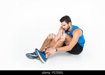 sportive young man lacing up sneakers before run on white Stock Photo