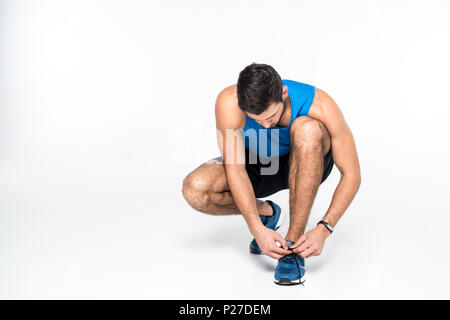 athletic young man lacing up sneakers before run on white Stock Photo