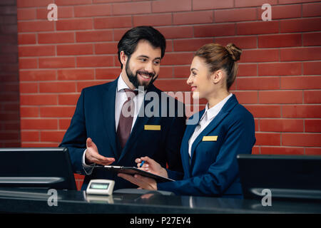 smiling hotel receptionists working together at counter Stock Photo