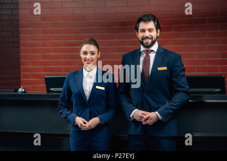 hotel receptionists standing together in front of counter and looking at camera Stock Photo
