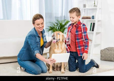 mother and son playing console games while their dog sitting on floor Stock Photo