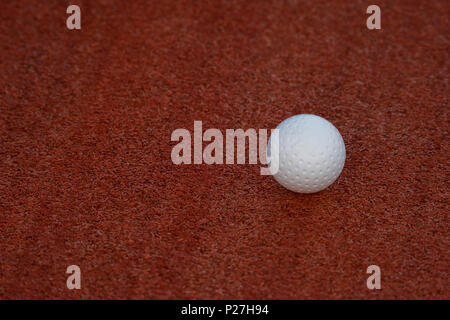 White ball for playing field hockey on the red grass background Stock Photo