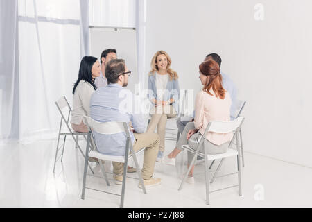 multiethnic middle aged people sitting on chairs and talking during group therapy Stock Photo