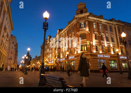 Moscow, Russia - September 21, 2017: People and historical building decorated by warm light at Arbat walking street during twilight with blue sky. Stock Photo
