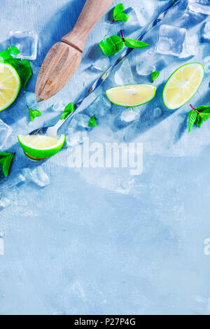 Mojito cocktail ingredients, mint, lime and ice cubes on a gray stone background with copy space. Lemon reamer or juicer in making summer drinks conce Stock Photo