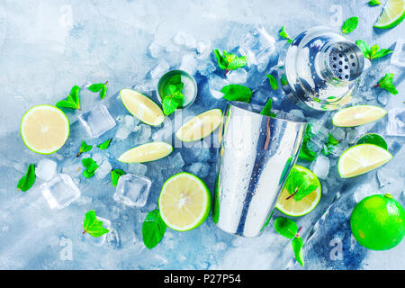 Fresh mojito cocktail ingredients, mint, lime and ice cubes on a gray stone background. Shaker and bar accessories flat lay. Summer drink concept with Stock Photo