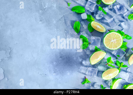 Mojito cocktail ingredients, mint, lime and ice cubes on a gray stone background with copy space. Making summer drinks close-up. Sunlight and refreshm Stock Photo