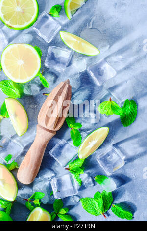 Lime juicer close-up with mint, lime and ice cubes. Mojito cocktail ingredients on a gray stone background with copy space. Summer drink concept sunli Stock Photo