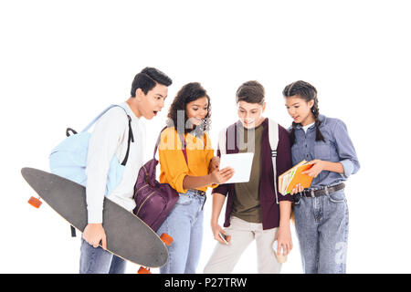 shocked multiracial students with backpacks and longboard using tablet together isolated on white Stock Photo
