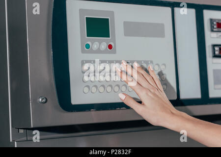 cropped shot of woman pressing buttons on industrial washing machine Stock Photo