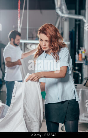 dry cleaning worker folding clean cloth at warehouse Stock Photo