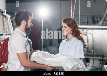 young smiling dry cleaning workers at warehouse Stock Photo