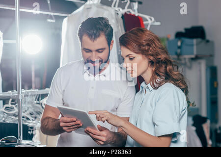 happy young dry cleaning workers using tablet together Stock Photo