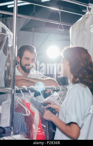 young dry cleaning workers talking at warehouse Stock Photo