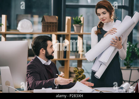 two architects discussing and working with blueprints in office Stock Photo