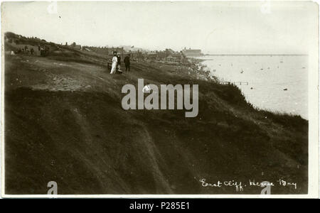 . Postcard photo of East Cliff at Herne Bay, Kent, England. The postcard is unused, but it is dated on the grounds that the Grand Pier Pavilion in the background was built in 1910, and the Kings Hall has not yet had its 1913 rebuild. The photographer was Fred C. Palmer of Tower Studio, Herne Bay, Kent, who is believed to have died 1936-1939. Points of interest: Among the posed group of people in the centre foreground, the lad on the grass is smiling cheekily, as if perhaps he has done this before. Could he be Palmer's son Leslie Reginald, born 1896? The large group in the top left distance mig Stock Photo