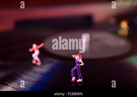 Miniature roller skating figures on vintage vinyl record in macro closeup Stock Photo