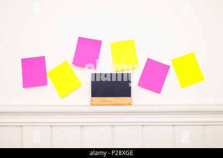 Empty colorful sticky notes and little blackboard on the wall . Stock Photo