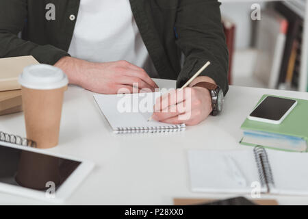 cropped image of student making notes in library Stock Photo