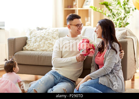 happy husband giving flowers to his wife at home Stock Photo