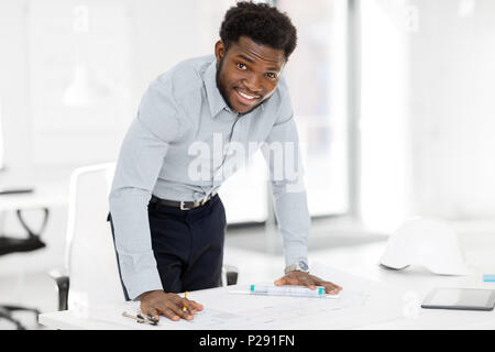 smiling african architect with blueprint at office Stock Photo