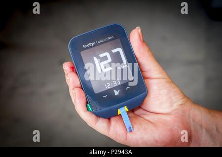 Woman patient with pregnancy diabetes holding in her hands a Freestyle Optium Neo glucometer after the blood testing with high glucose level results. Stock Photo