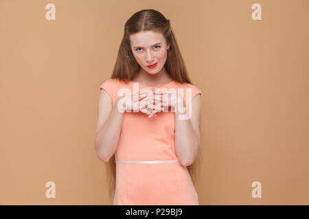 cunning plan, looking at camera. portrait of emotional cute, beautiful woman with makeup and long hair in pink dress. indoor, studio shot, isolated on Stock Photo