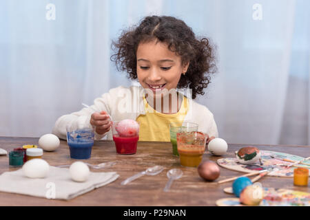 happy african american child painting easter eggs in glasses with paints Stock Photo