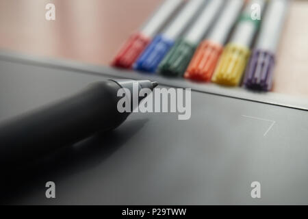 Stylus pen on graphic tablet with colored markers in background Stock Photo