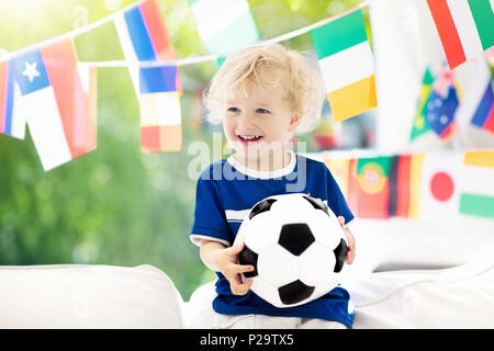 Child watching football game on tv. Little boy in France tricot watching soccer game during championship. Kid fan cheering and supporting national tea Stock Photo