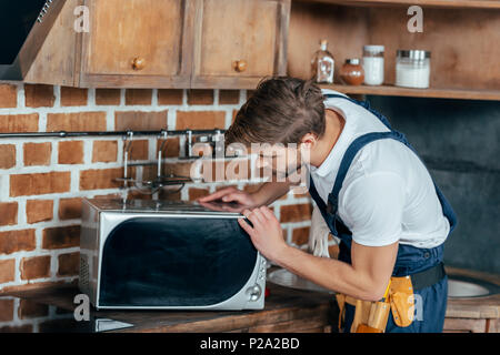 professional young handyman repairing microwave oven in kitchen Stock Photo