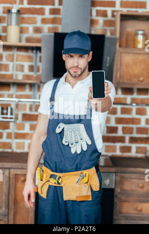 handsome young professional home master showing smartphone with blank screen Stock Photo