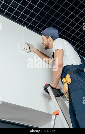 low angle view of young electrician fixing home alarm Stock Photo