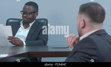 Serious afro-american businessmen working through papers and discussing financial report with his partner Stock Photo