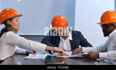 Multiracial colleagues reading construction documents, discussing it Stock Photo