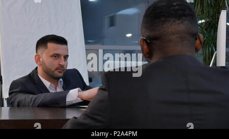 Two young businessmen discussing project at meeting Stock Photo