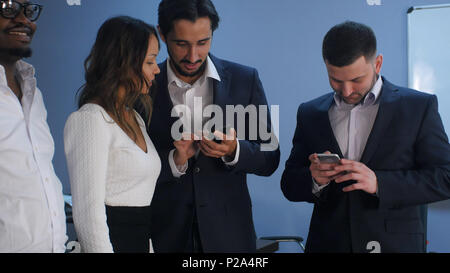 Group of five multiracial business people standing and using smartphones Stock Photo
