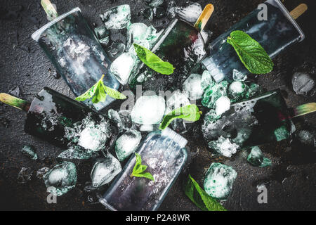 Trendy food, Asian vegan desserts, homemade ice cream popsicles with algae spirulina, served with mint in glasses with ice, dark rusty background copy Stock Photo