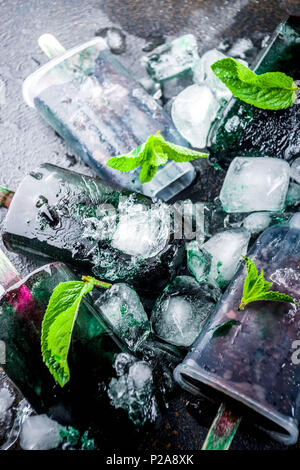 Trendy food, Asian vegan desserts, homemade ice cream popsicles with algae spirulina, served with mint in glasses with ice, dark rusty background copy Stock Photo