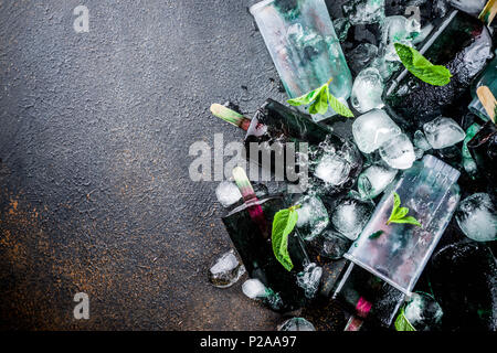 Trendy food, Asian vegan desserts, homemade ice cream popsicles with algae spirulina, served with mint in glasses with ice, dark rusty background copy Stock Photo