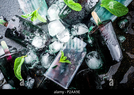 Trendy food, Asian vegan desserts, homemade ice cream popsicles with algae spirulina, served with mint in glasses with ice, dark rusty background copy Stock Photo