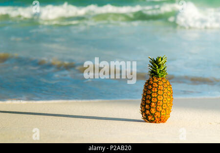 Whole pineapple on the beach with the sea in the background Stock Photo