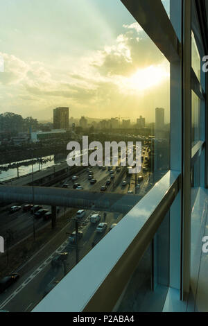 View of car traffic on avenue through corporate building window at dusk in the city of Sao Paulo. Stock Photo
